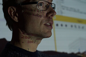 a mans head in profile in froft of a screen