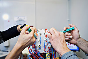 two sets of hands working with the top of a eeg-cap