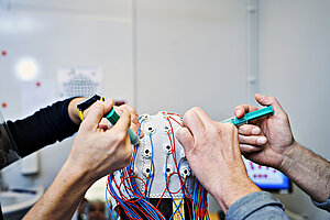 two sets of hands working with the top of a eeg-cap