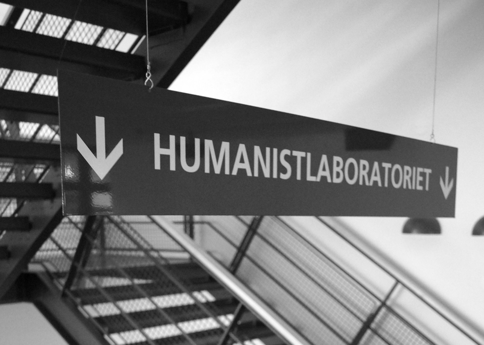 black and white picture: a sign saying "Humanistlaboratoriet" in fron of a staircase