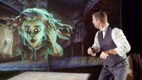 Photograph with a virtual green ghost to the left that looks suprised and has streaming hair around her face. To the right, a man is half turned around, looking suprised at the ghost. 